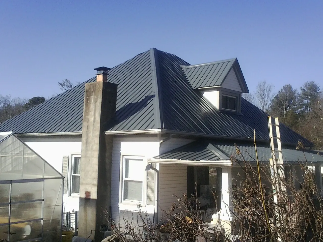 Dark blue standing seam metal roof on a white farmhouse with dormer — Slate & Tile Roof Repair by Roofing Brothers in Chillicothe